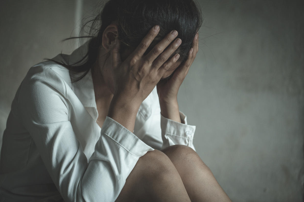 Woman crouched with face in hands. 