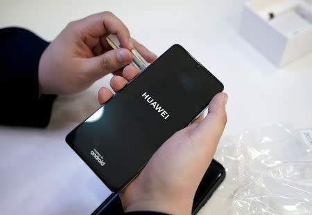 FILE PHOTO: A salesman turns on a new Huawei P30 smartphone for a customer after Huawei's P30 and P30 Pro went on sale at a Huawei store in Beijing, China, April 11, 2019. REUTERS/Jason Lee/File Photo