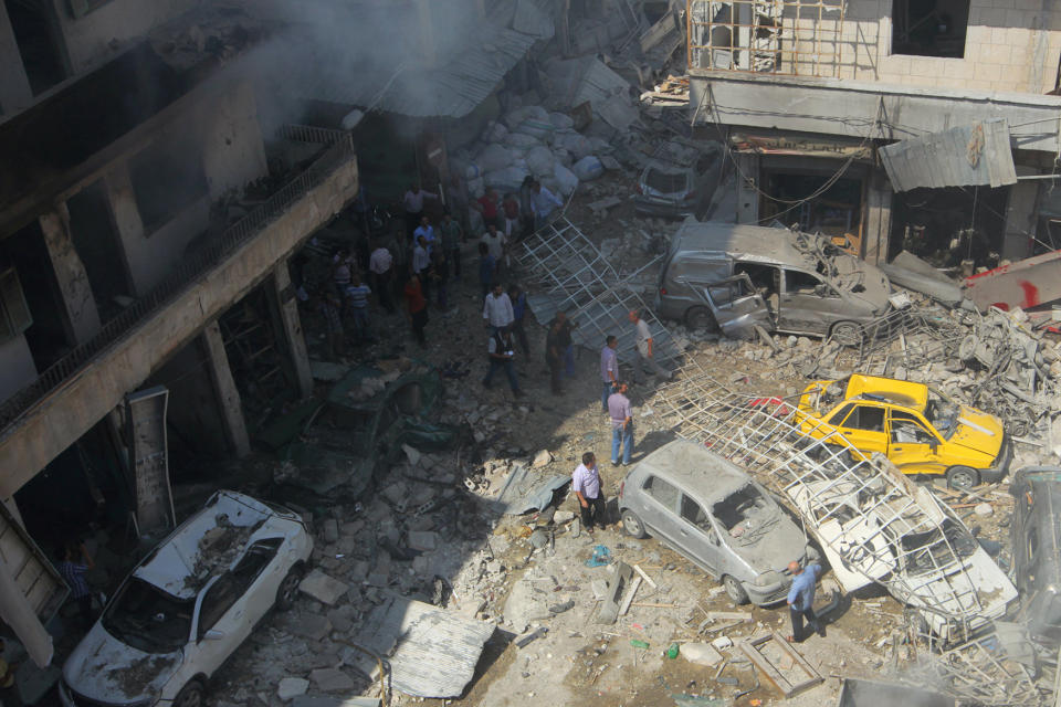 Residents inspect a damaged site after airstrikes on a market in the rebel controlled city of Idlib