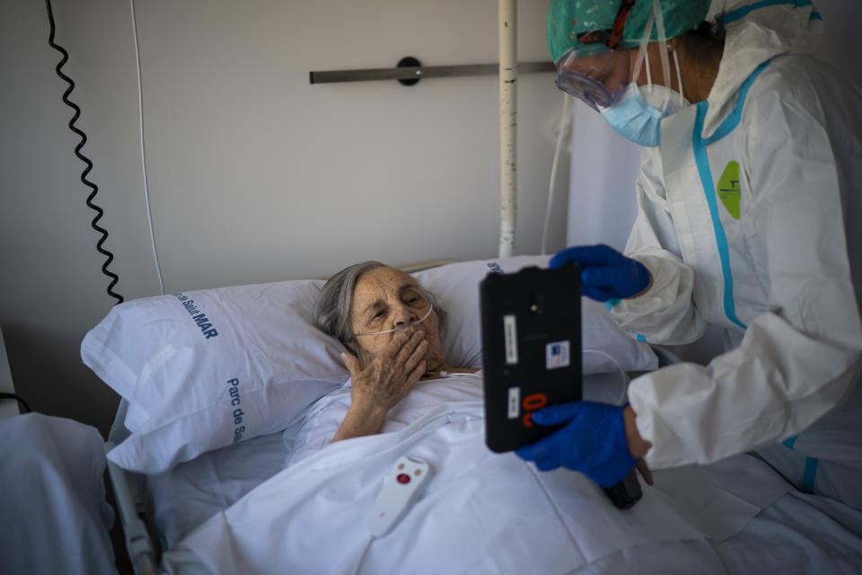 Nurse Marta Fernandez holds up a tablet computer over the chest of 94-year-old Maria Teresa Argullos Bove so that she can speak to her sister, children and grandchildren from her hospital bed at the COVID-19 ward at the hospital del Mar in Barcelona, Spain, Nov. 18, 2020. The image was part of a series by Associated Press photographer Emilio Morenatti that won the 2021 Pulitzer Prize for feature photography. (AP Photo/Emilio Morenatti)