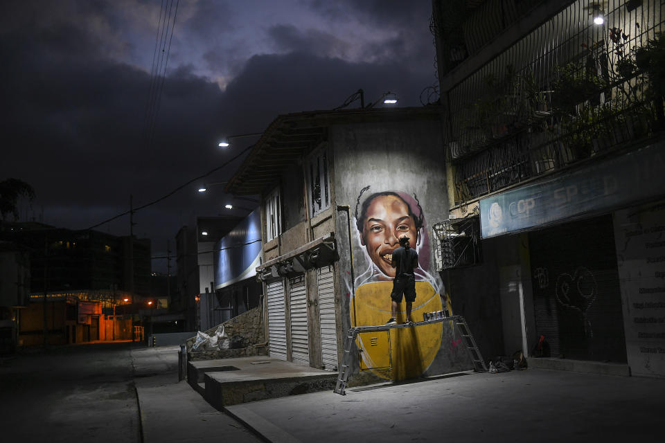 Street artist Wolfgang Salazar works on his mural featuring Venezuelan athlete Yulimar Rojas, in the Boleita neighborhood of Caracas, Venezuela, Saturday, Jan. 2, 2021. Salazar said he chose to paint Rojas because she embodies the potential of Venezuelan greatness. (AP Photo/Matias Delacroix)