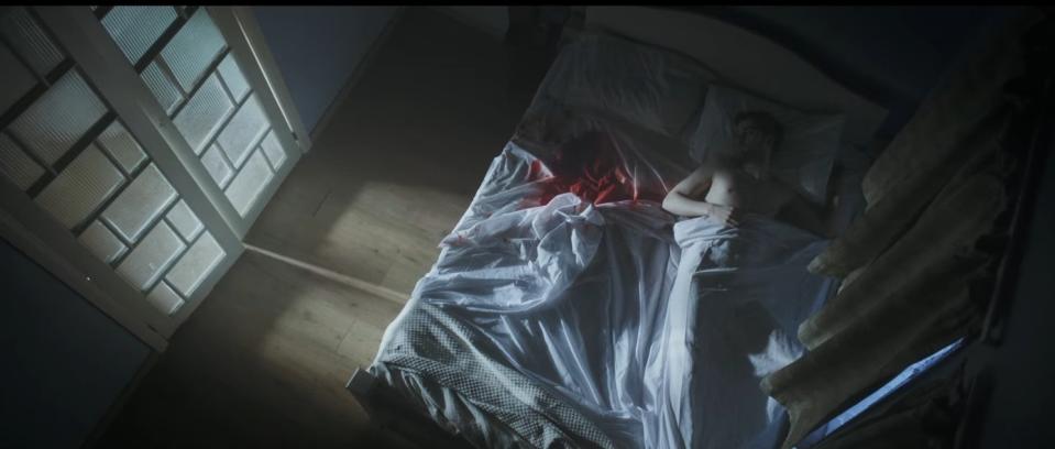 A man lays in a bed soaked with blood