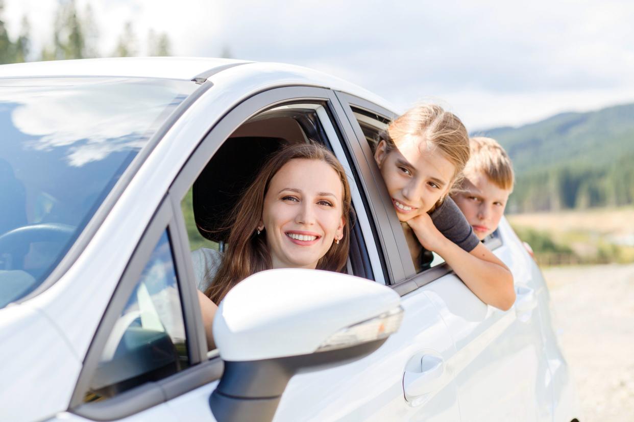 happy young mom and her children sitting in a car