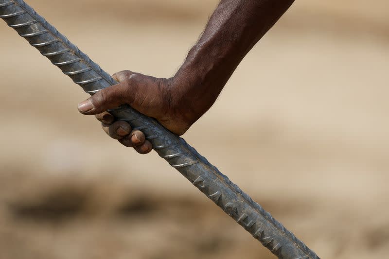 Banwari Singh, 40, a construction worker, holds an iron rod with his bare hand at a construction site during a hot summer day in New Delhi