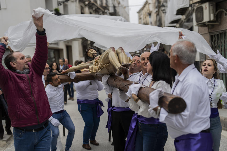 Members of the "Vera Cruz" Catholic brotherhood cover a figure of Jesus Christ with a plastic sheet to protect it from the rain, during a Holy Week procession in the southern town of Quesada, Spain, Friday, March 29, 2024. (AP Photo/Bernat Armangue)