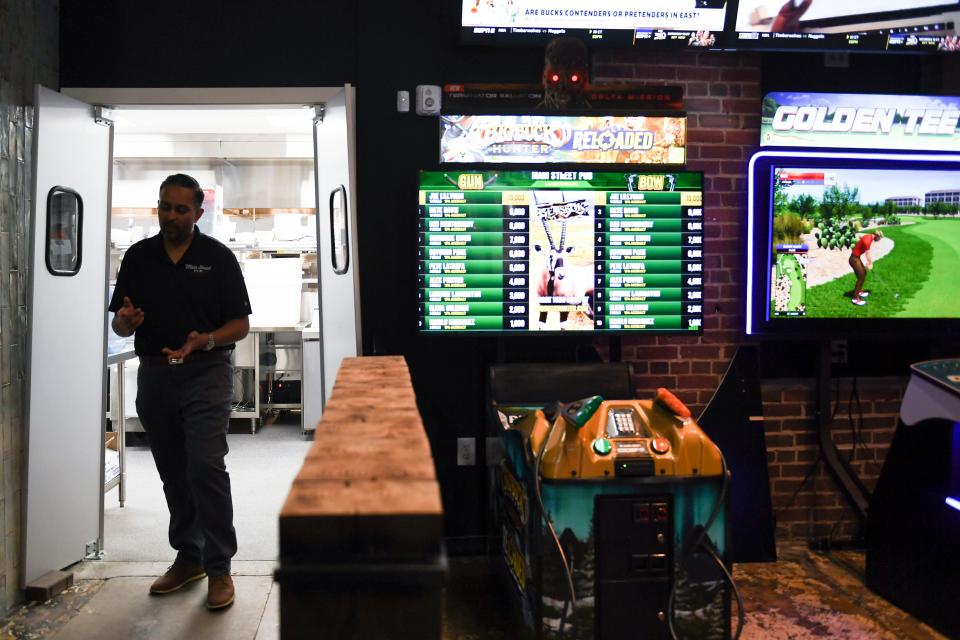 Raj Patel, owner of Main Street Pub, walks out of the newly renovated kitchen in Spartanburg, S.C., on Wednesday, April 10, 2024. Patel installed two brand new arcade games, right, during the restaurant's remodel.