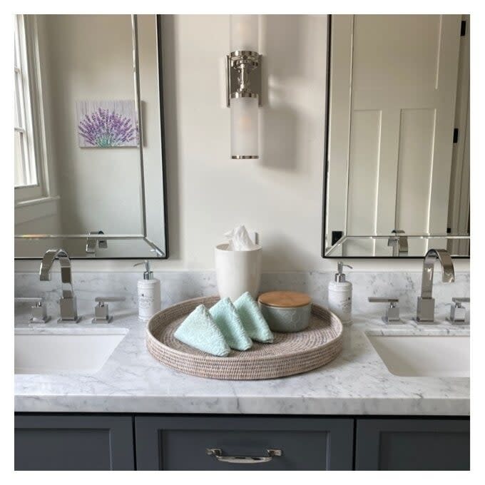 the circular rattan tray on a bathroom vanity holding towels