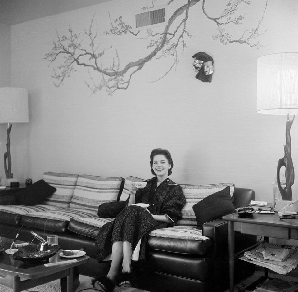 <p>Natalie Wood smiles as she enjoys a cup of tea from the couch of her Los Angeles living room in 1957. </p>