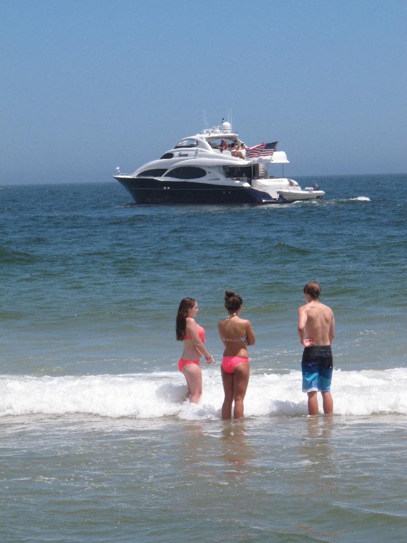 In this July 5, 2013 photo, swimmers in Point Pleasant Beach N.J. watch a large yacht turn around near the beach. A new Monmouth University/Asbury Park Press poll finds nearly 40 percent of New Jerseyans spent less time at the shore this summer, many fearing that businesses had not reopened after Superstorm Sandy last October. (AP Photo/Wayne Parry)