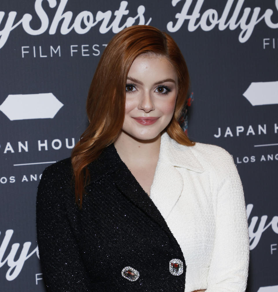 Ariel smiling at the camera, wearing a blazer jacket that's black on one side and white on the other