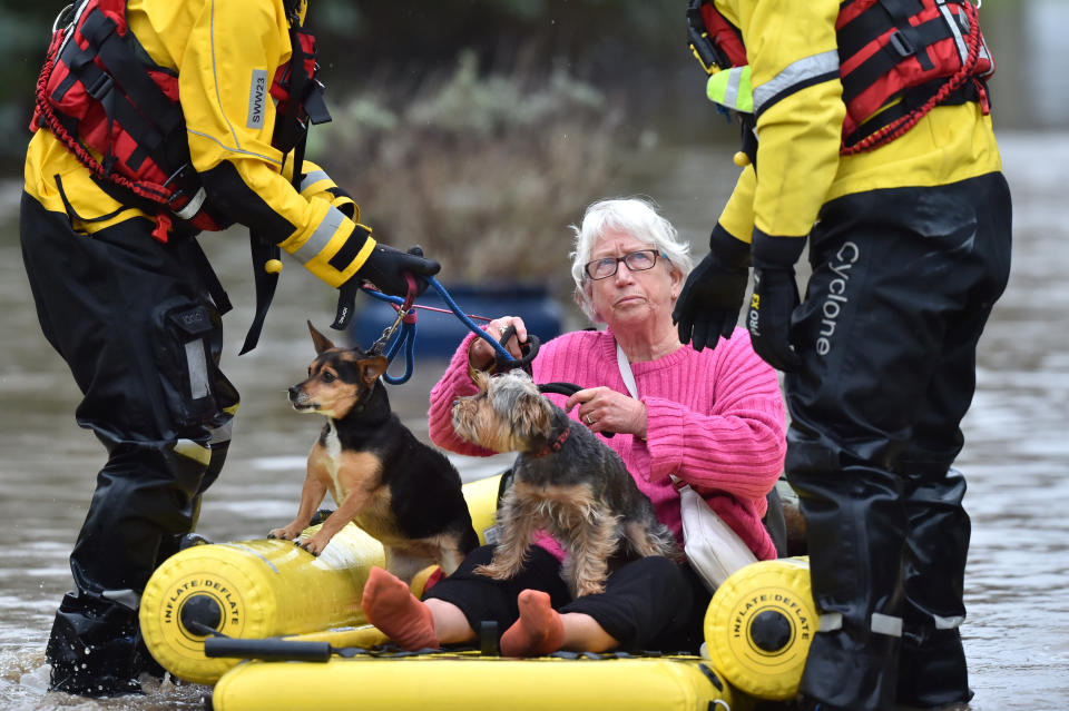 A woman and her two dogs are rescued from the floods. (PA)