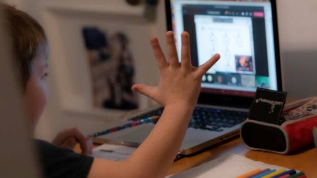 An elementary student waves to their class while doing online learning. Jay Wilson told The Morning Edition his researchers are seeing less bullying and more flexibility in online learning.  (Ivanoh Demers/Radio-Canada - image credit)