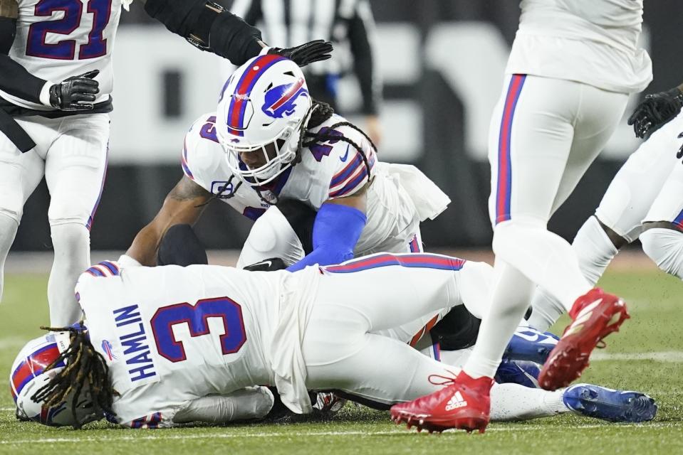 Buffalo Bills safety Damar Hamlin (3) lies on the turf after making a tackle on Cincinnati Bengals wide receiver Tee Higgins, blocked from view, as Buffalo Bills linebacker Tremaine Edmunds (49) assists at the end of the play during the first half of an NFL football game between the Cincinnati Bengals and the Buffalo Bills, Monday, Jan. 2, 2023, in Cincinnati. After getting up from the play, Hamlin collapsed and was administered CPR on the field. (AP Photo/Joshua A. Bickel)