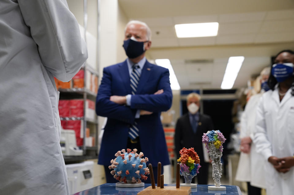 FILE - In this Thursday, Feb. 11, 2021 file photo, President Joe Biden visits the Viral Pathogenesis Laboratory at the National Institutes of Health (NIH) in Bethesda, Md. At bottom center is a model of the COVID-19 virus. On Friday, Feb. 26, 2021, The Associated Press reported on stories circulating online incorrectly asserting Biden restored taxpayer funding for the Wuhan Institute of Virology. Social media users are falsely claiming the Biden administration is bankrolling the Wuhan Institute of Virology, a Chinese lab which has faced unproven allegations that the coronavirus leaked from the facility leading to the global COVID-19 pandemic. (AP Photo/Evan Vucci)