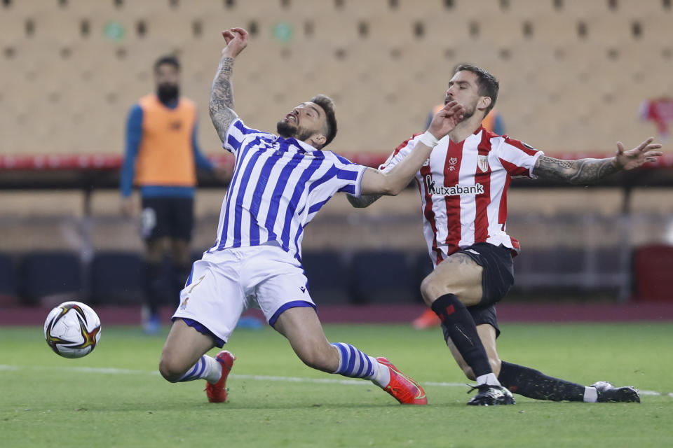 Athletic Bilbao's Inigo Martinez, right, fouls Real Sociedad's Portu, in the penalty box during the final of the 2020 Copa del Rey, or King's Cup, soccer match between Athletic Bilbao and Real Sociedad at Estadio de La Cartuja in Sevilla, Spain, Saturday April 3, 2021. The game is the rescheduled final of the 2019-2020 competition which was originally postponed due to the coronavirus pandemic. (AP Photo/Angel Fernandez)