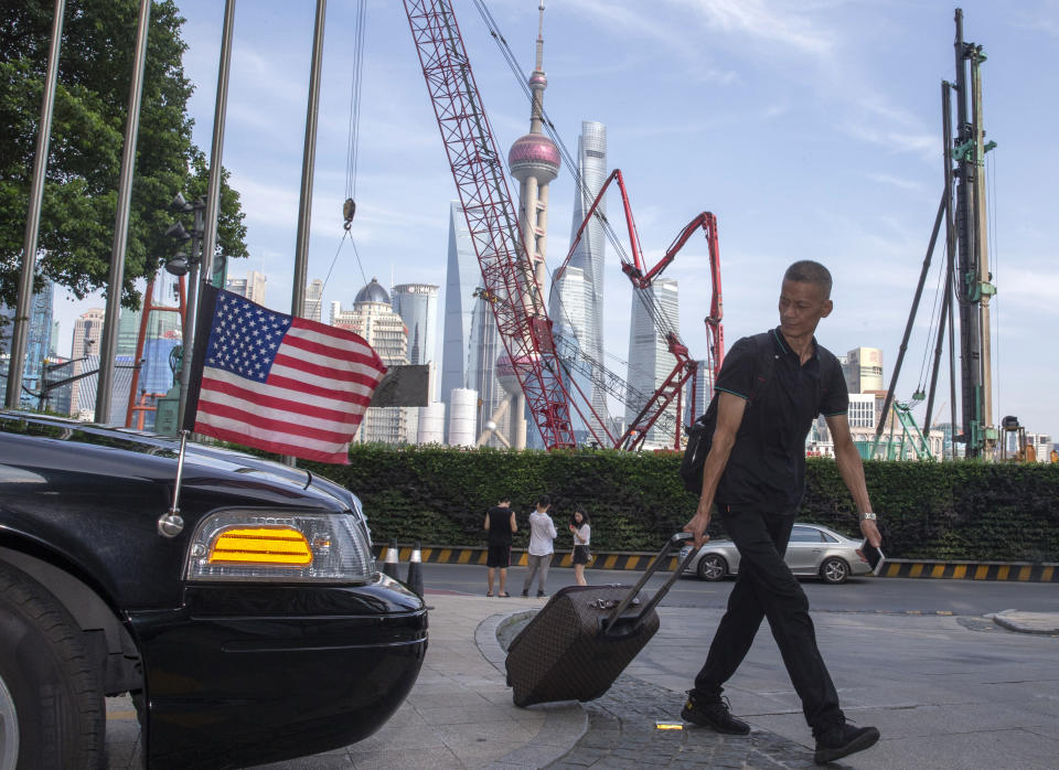 FILE - In this July 30, 2019, file photo, a traveller pulls a trolley past a U.S. embassy car outside a hotel in Shanghai. China has announced it will raise tariffs on $75 billion of U.S. products in retaliation for President Donald Trump's planned Sept. 1 duty increase in a war over trade and technology policy. (AP Photo/Ng Han Guan, File)