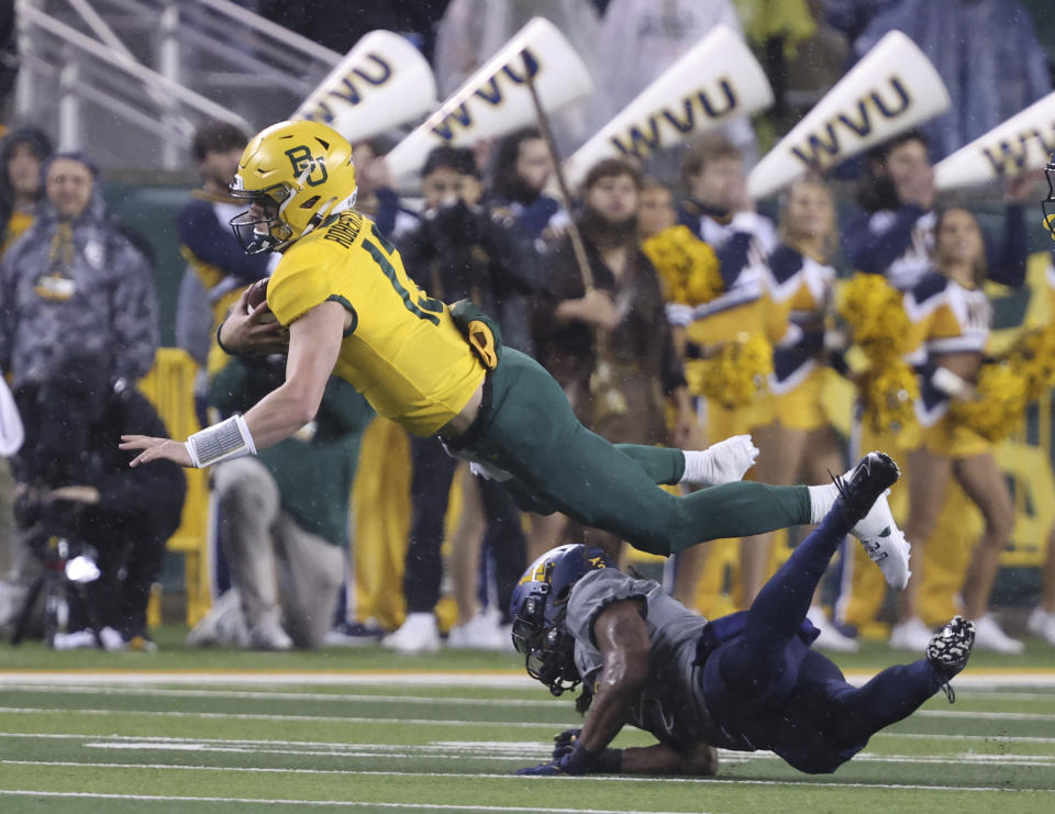 Baylor quarterback Sawyer Robertson, top, leaps over the West Virginia safety Aubrey Burks, bottom, in the first half of an NCAA college football game, Saturday, Nov. 25, 2023, in Waco, Texas. (Rod Aydelotte/Waco Tribune-Herald, via AP)