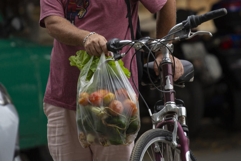 A shopper leaves the 17 and K Market on a bike in Havana, Cuba, Friday, Dec. 23, 2022. In October, the Cuban government reported that inflation had risen 40% over the past year and had a significant impact on the purchasing power for many on the island. (AP Photo/Ismael Francisco)