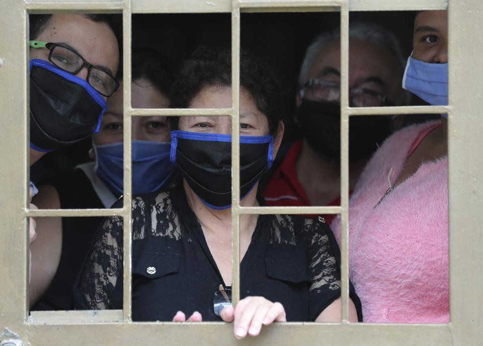 A family peers from the window of their home as they wait to receive boxes of free food, during a lockdown to curb the spread of the new coronavirus, in Bogota, Colombia, Monday, May 4, 2020. The U.N. World Food Program is warning that upward of at least 14 million people could go hungry in Latin America as the coronavirus pandemic rages on, shuttering people in their homes, drying up work and crippling the economy. (AP Photo/Fernando Vergara)