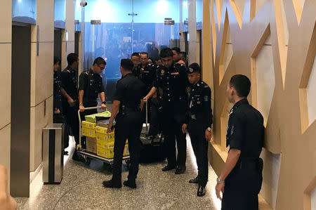 FILE PHOTO: Policemen escort a trolley of documents seized by the Malaysian Anti-Corruption Commission (MACC) at the Felda Global Ventures Holdings headquarters, in Malaysia's capital Kuala Lumpur June 8, 2017. REUTERS/Emily Chow/File Photo