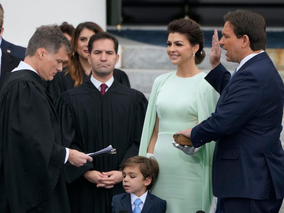 Florida Gov. Ron DeSantis, right, is sworn by Florida Supreme Court Chief Justice Carlos Muniz, left, to begin his second term during an inauguration ceremony outside the Old Capitol Tuesday, January 3, 2023, in Tallahassee, Florida. Looking on is DeSantis' wife Casey, second from right, and their son Mason.