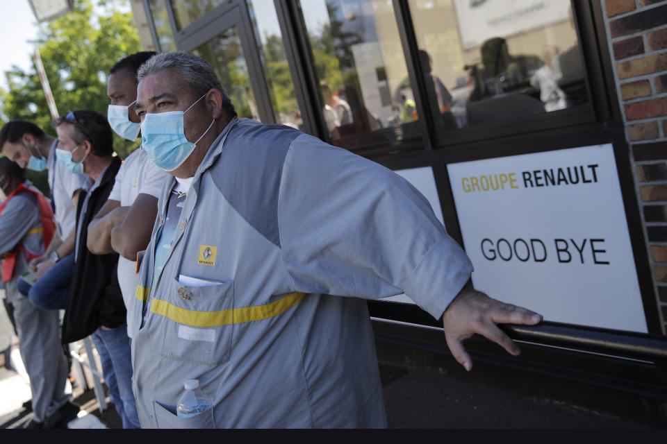 Protesting Renault workers stand outside their plant Friday, May 29, 2020 in Choisy-le-Roi, outside Paris. Struggling French carmaker Renault announced 15,000 job cuts worldwide as part of a 2 billion euros cost-cutting plan over three years. The cost-cutting plan comes as Renault came into the virus crisis in particularly bad shape. Its alliance with Nissan and Mitsubishi is a major global auto player but has struggled since the 2018 arrest of its longtime star CEO Carlos Ghosn. (AP Photo/Christophe Ena)