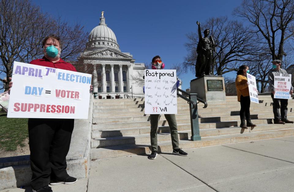 A group with C.O.V.I.D., Citizens Outraged Voters in Danger, protest wearing masks outside the State Capitol during a special session regarding the spring election in Madison, Wis., Saturday, April 4, 2020.