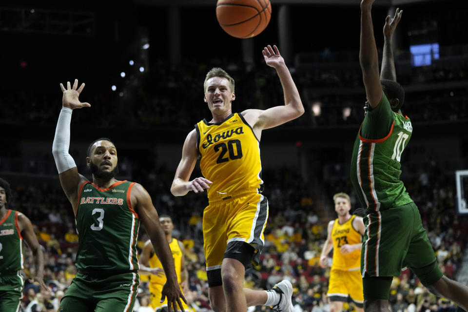 Iowa forward Payton Sandfort (20) fights for a loose ball with Florida A&M guard Morrell Schramm (3) and forward Chase Barrs (10) during the first half of an NCAA college basketball game, Saturday, Dec. 16, 2023, in Des Moines, Iowa. (AP Photo/Charlie Neibergall)