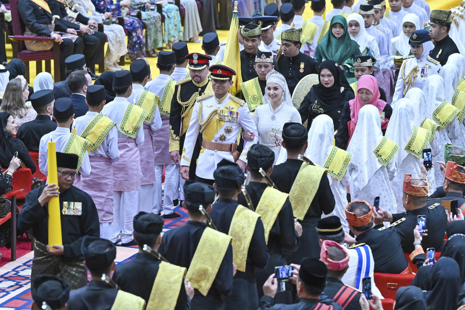 In this photo released by Brunei's Information Department, Brunei's Prince Abdul Mateen, center left, and bride Anisha Rosnah walk down the aisle during their wedding reception at Istana Nurul Iman in Bandar Seri Begawan, Brunei Sunday, Jan. 14, 2024. (Brunei's Information Department via AP)