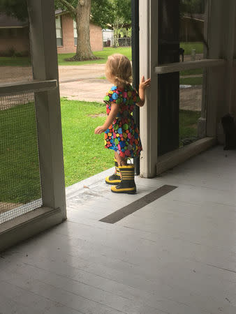 Emily Price looks out the front door of her family's duplex on Gillis W. Long National Guard Center in Carville, Louisiana, U.S., in this June 20, 2017 handout photo obtained by Reuters October 2, 2018. Coryn Price/Handout via REUTERS