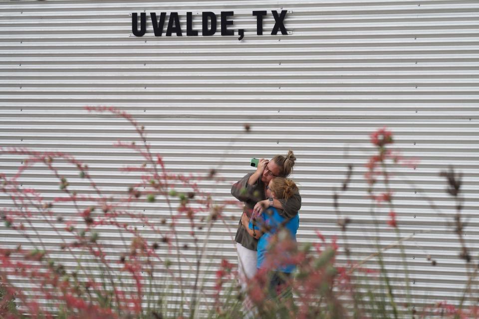 A woman cries and hugs a young girl while on the phone outside the Willie de Leon Civic Center