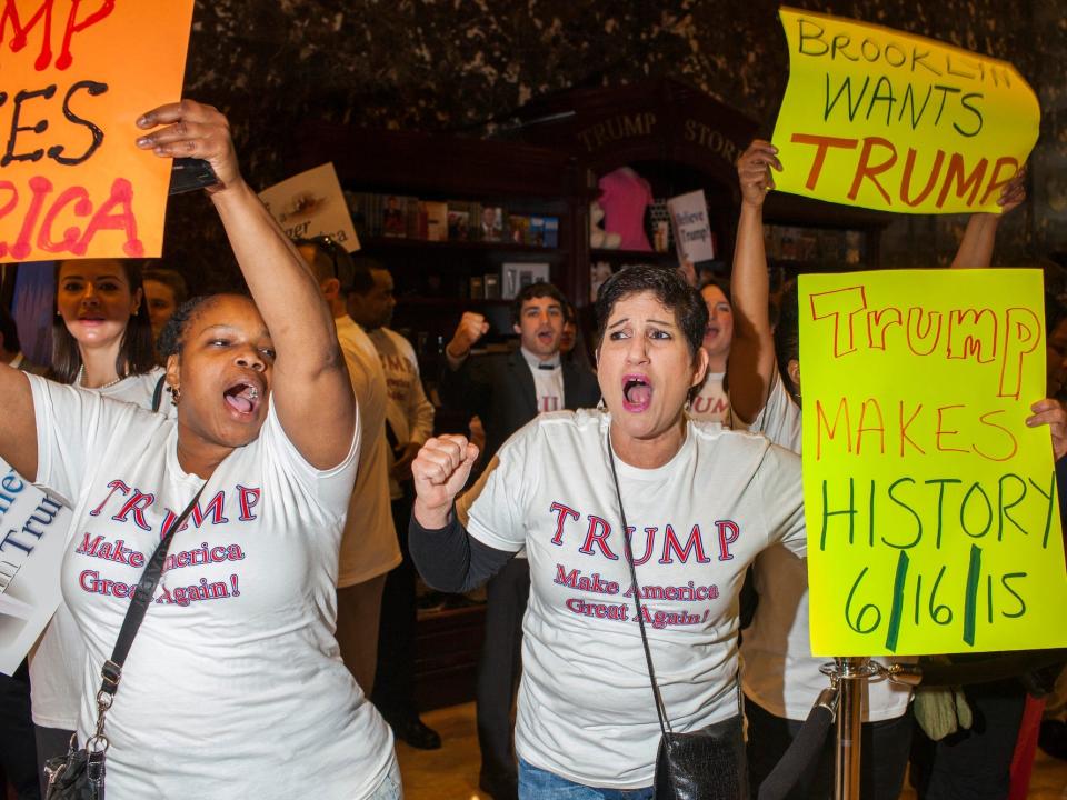 Donald Trump supporters wave signs and wear Trump T-shirts at his 2016 presidential campaign announcement at Trump Tower.