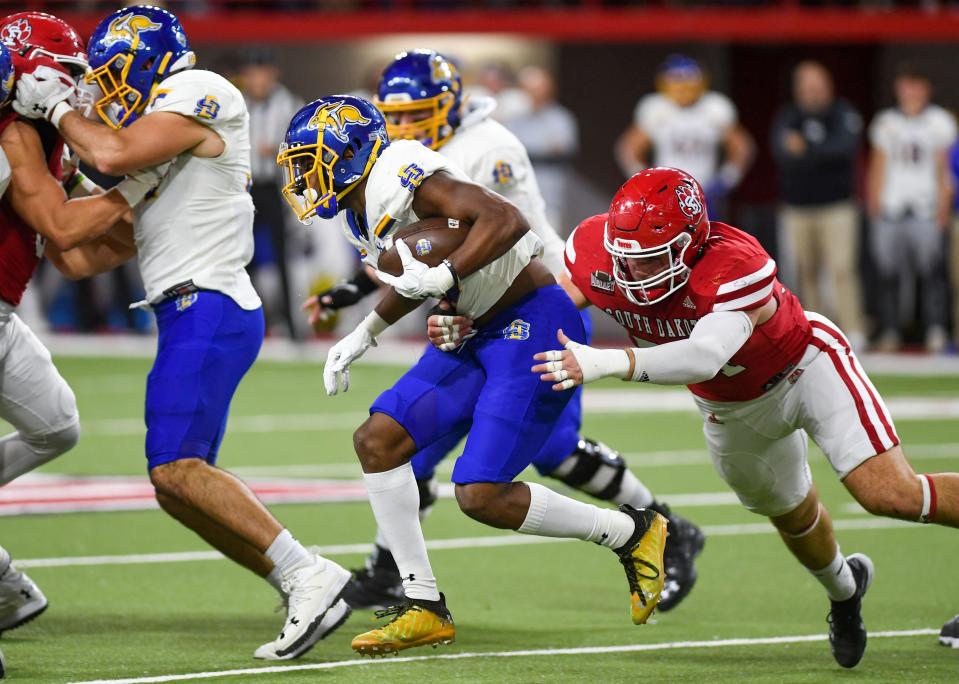 South Dakota State's Pierre Strong, Jr. runs the ball as South Dakota's Nick Gaes lunges to tackle him on Saturday, November 13, 2021, at the DakotaDome in Vermillion.