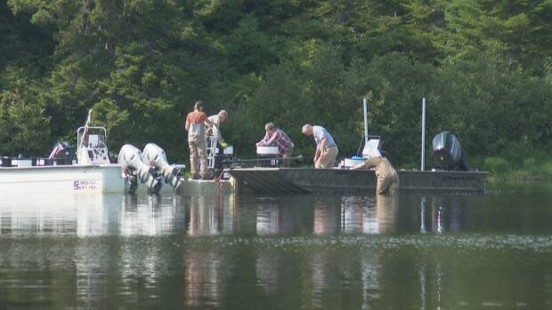 Crews remove barrels of rotenone from boats to be taken away after days of delays caused by Wolastoqey grandmothers and mothers paddling on the lake. (Shane Fowler/CBC - image credit)