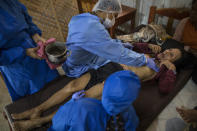 Comando Matico volunteer Isai Eliaquin Sanancino, treats Sara Magin, who suffers from COVID-19 symptoms, applying an ancestral practice of the Indigenous Shipibo, in Pucallpa, in Peru’s Ucayali region, Tuesday, Sept. 1, 2020. Unlike in hospitals, volunteers equipped in full protective gear, get close to patients, giving them words of encouragement and touching them through massage. (AP Photo/Rodrigo Abd)