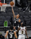 San Antonio Spurs guard Dejounte Murray, center, scores over Denver Nuggets forward Will Barton (5) during the second half of an NBA basketball game in San Antonio, Friday, Jan. 29, 2021. (AP Photo/Eric Gay)