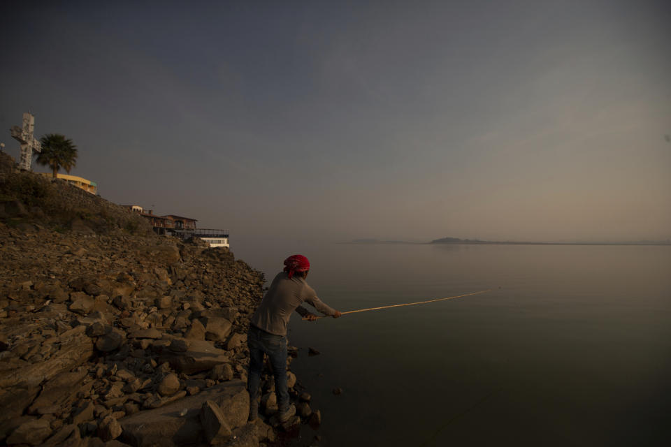 A man fishes off the banks of the Villa Victoria Dam, the main water supply for Mexico City residents, on the outskirts of Toluca, Mexico Thursday, April 22, 2021. Drought conditions now cover 85% of Mexico, and in areas around Mexico City and Michoacán, the problem has gotten so bad that lakes and reservoirs are drying up. (AP Photo/Fernando Llano)