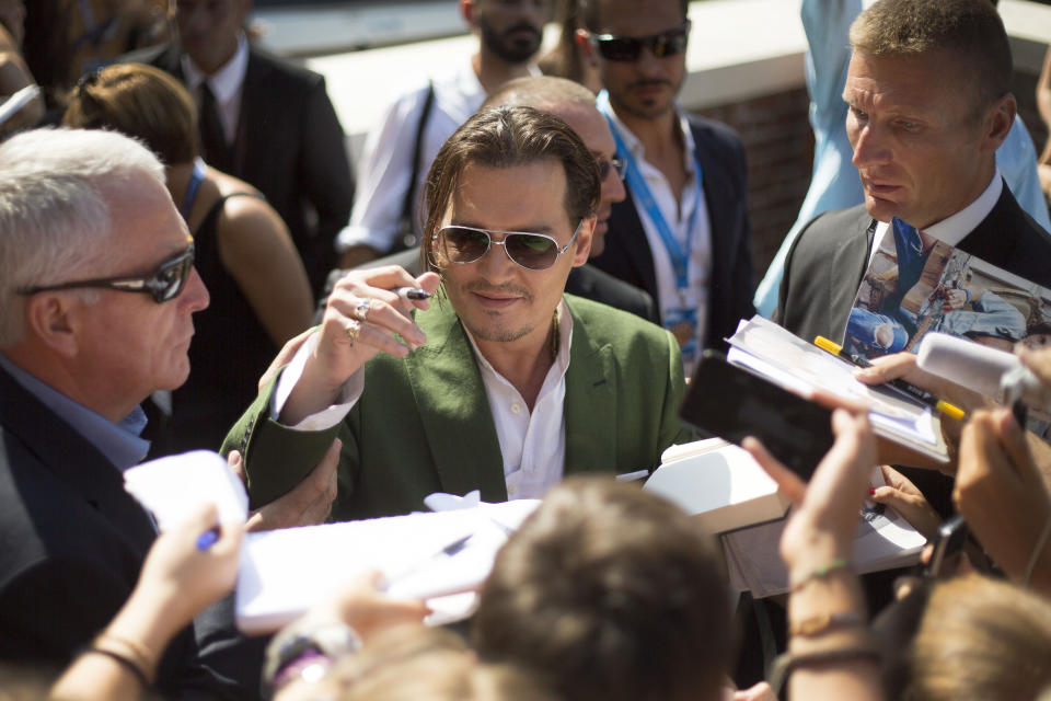 File - Johnny Depp signs autographs for fans as he departs after a photo call for 'Black Mass' at the Venice Film Festival. The 77th Venice Film Festival will kick off on Wednesday, Sept. 2, 2020, but this year's edition will be unlike any others. Coronavirus restrictions will mean fewer Hollywood stars, no crowds interacting with actors and other virus safeguards will be deployed. (Photo by Joel Ryan/Invision/AP, File)
