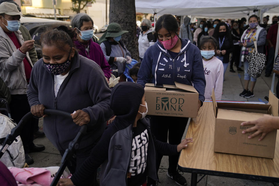 People pick up boxes of groceries at a food bank held at Los Angeles Boys & Girls Club in the Lincoln Heights neighborhood of Los Angeles, Thursday, Dec. 17, 2020. "This neighborhood is hard hit by COVID-19. Our families work in service industry jobs," said Carlyn Oropez, director of operations at the facility. "Most of the people here have had a reduction in hours, reduction in pay, or have lost their jobs. They are coming here for help with basic needs." (AP Photo/Jae C. Hong)