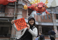 A woman holds a spring couplet with dragon patterns that she drew herself for the upcoming Lunar New Year celebrations at the Dihua street market in Taipei, Taiwan, Thursday, Feb. 8, 2024. Taiwanese shoppers started hunting for delicacies, dried goods and other bargains at the market ahead of the Lunar New Year celebrations which fall on Feb. 10 this year. (AP Photo/Chiang Ying-ying)