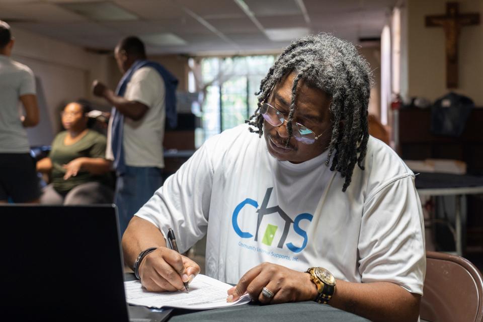 Community & Home Supports resource navigator Timothy Desaussure Jr., right, fills out paperwork while helping a man get signed up for assistance at  St. John's Community Center in Detroit on Wednesday, May 31, 2023.