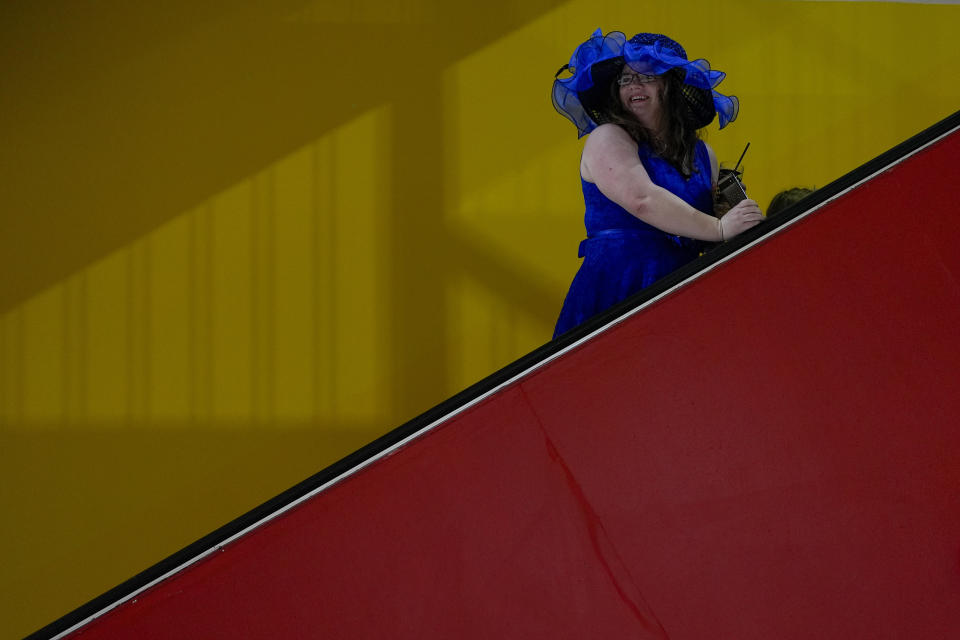 Caroline Lewis wears a matching dress and hat as she takes an escalator ahead of the Black-Eyed Susan horse race at Pimlico Race Course, Friday, May 17, 2024, in Baltimore. (AP Photo/Julia Nikhinson)