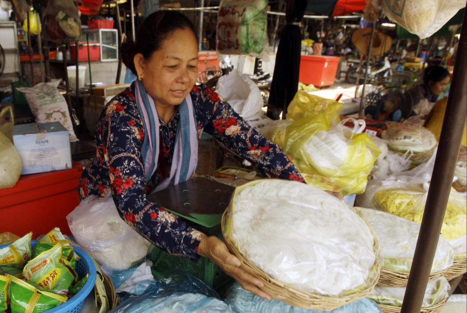 In this June 4, 2019, photo, a Cambodian vendor prepares baskets loaded with the traditional noodle, called "Num Banh-chok", for selling at a local market, in Phnom Penh, Cambodia. The bitter decadeslong rivalry between Hun Sen, Cambodia's strongman leader, and Sam Rainsy, the self-exiled chief political rival and critic, has sometimes played out in deadly violence. But on Sunday, soup rather than blood was likely to be spilled. (AP Photo/Heng Sinith)