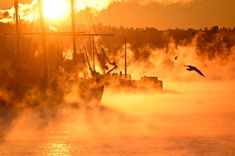 El vapor se eleva desde el agua alrededor de un histórico velero tri-master amarrado en un puerto de Oslo el 5 de enero de 2024. Temperaturas frías inusuales de alrededor de -22 grados. (Olivier MORIN / AFP)