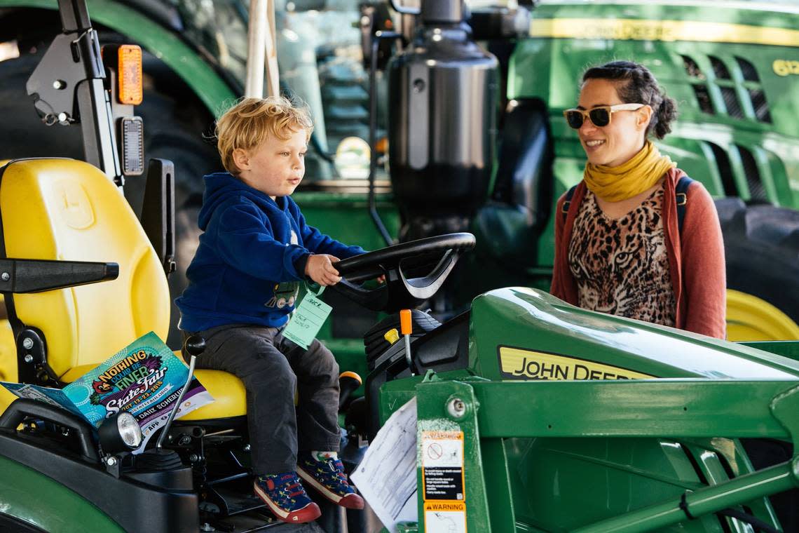 Asa Anderson, left, sits on a John Deere tractor while his mom, Kavanah, right, watches during the final day of the North Carolina State Fair in Raleigh, N.C. on Sunday, Oct. 23, 2016.