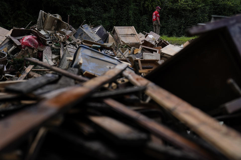 FILE - A man stands near a pile of debris as residents start to clean up and rebuild in Fleming-Neon, Ky., Aug. 5, 2022, after massive flooding the previous week. Ten years ago scientists warned the world about how climate change would amplify extreme weather disasters. There are now deadly floods, oppressive heat waves, killer storms, devastating droughts and what scientists call unprecedented extremes as predicted in 2012. (AP Photo/Brynn Anderson, File)