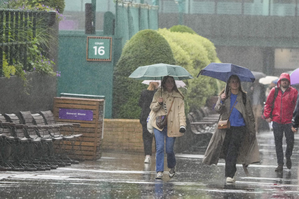 Spectators walk around the venue as rain delays the start of play ahead of third round matches at the Wimbledon tennis championships in London, Friday, July 5, 2024. (AP Photo/Mark Baker)