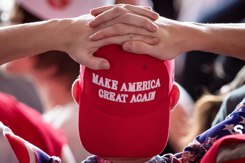 A man wearing a "Make America Great Again" hat waits for President Donald Trump to arrive for a campaign rally in 2019.