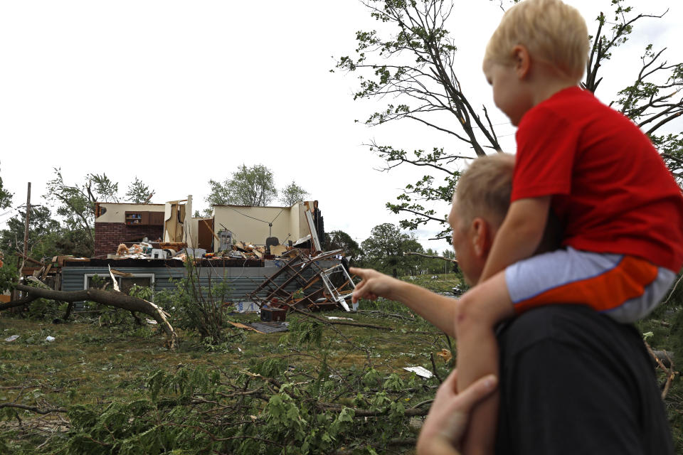 Woodridge, Ill., resident Jesse Wallace points out one of the severely damaged homes to his three-year-old son Chris Wallace, after a tornado passed through the area on Monday, June 21, 2021. (AP Photo/Shafkat Anowar)