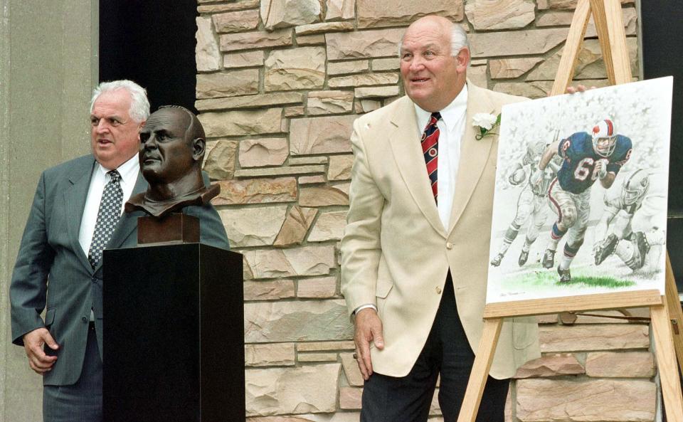 Penerima Hall of Fame Sepak Bola Pro 1999 Billy Shaw (kanan) berpose dengan patung perunggunya bersama presenternya, mantan pelatih kepala Buffalo Bills Eddie Abramoski (kiri), pada upacara Induksi Hall of Fame 07 Agustus 1999, di Pro Football Hall Ketenaran di Canton, Ohio. Shaw memainkan lini ofensif untuk Buffalo Bills. Foto AFP / David MAXWELL (Foto oleh DAVID MAXWELL / AFP) (Kredit foto harus dibaca DAVID MAXWELL/AFP via Getty Images)